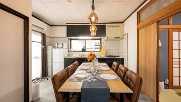 A dining area with a wooden table set for four, a brown leather chair, and a hanging light fixture.