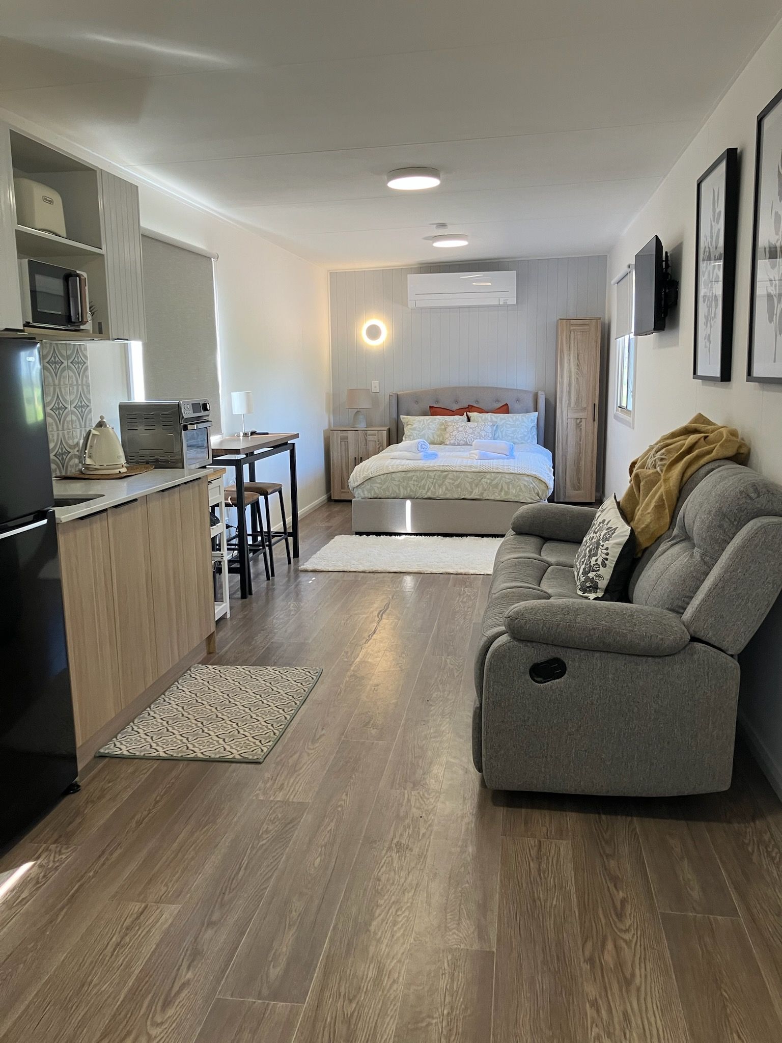 A compact living space with a kitchenette, a sofa, a bed, and a dining area.