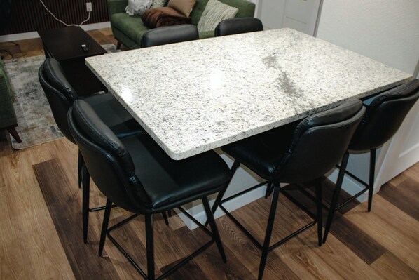 Een eetgedeelte met een granieten tafel en vier zwarte stoelen.