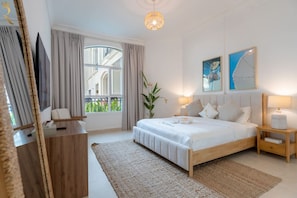 A modern bedroom with a large bed, a bedside table, a nightstand, a window with curtains, and a view of the outside. - 2BR | Balcony | Yas Island | Pool & Gym (Abu Dhabi)