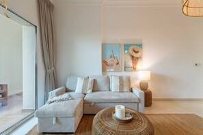 Ein modernes Wohnzimmer mit einer Couch, einem Beistelltisch und einer Lampe. An der Wand befinden sich zwei gerahmte Bilder.