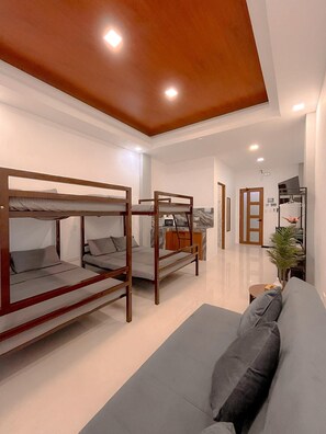 A modern hotel room with bunk beds, a sofa, a small kitchen area, and a hallway leading to other rooms. - The Island Palms Homestay (Alaminos City)