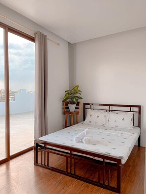 A bedroom with a bed, a potted plant, and a view through a large window. - The Island Palms Homestay (Alaminos City)
