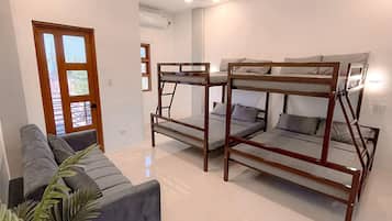 A modern room with bunk beds, a sofa, a coffee table, and a potted plant.
