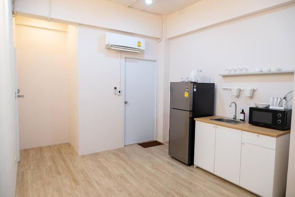 A compact kitchen with a refrigerator, microwave, sink, and white cabinets.