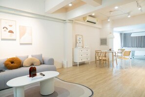 A modern hotel room with a sofa, a dining table, and a small kitchen area. - Lumi Minimal Residence (Krung Thep Maha Nakhon)