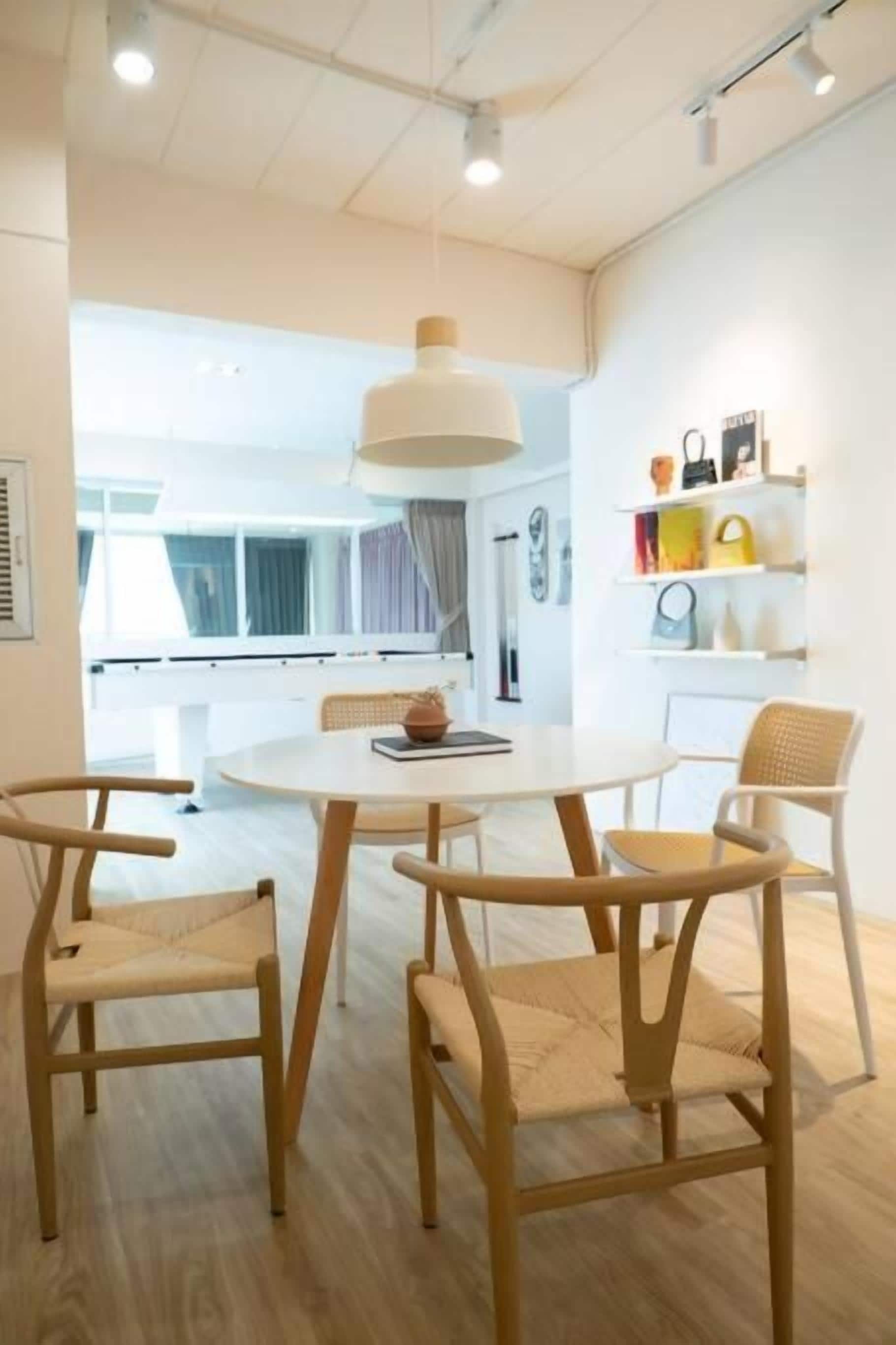 A modern dining area with a round table and four chairs, a hanging light fixture, and a view of the outdoors.