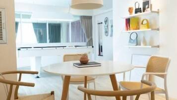 A modern dining area with a round table and four chairs, a hanging light fixture, and a view of the outdoors.