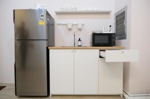 A compact kitchen with a stainless steel refrigerator, a microwave, a sink, and a white cabinet. - Lumi Minimal Residence (Krung Thep Maha Nakhon)