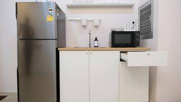 Una cocina compacta con un refrigerador de acero inoxidable, un microondas y una pequeña encimera.