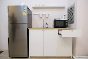 Una cocina compacta con un refrigerador de acero inoxidable, un microondas y una pequeña encimera.