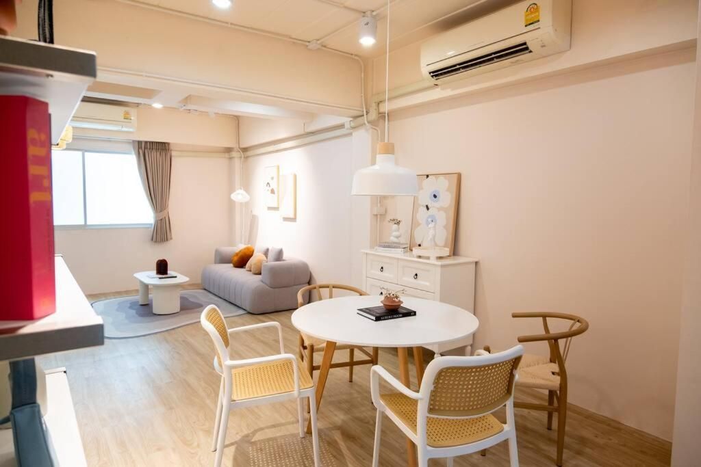 Una habitación de hotel moderna con una mesa redonda, sillas blancas, un sofá y una mesita auxiliar.