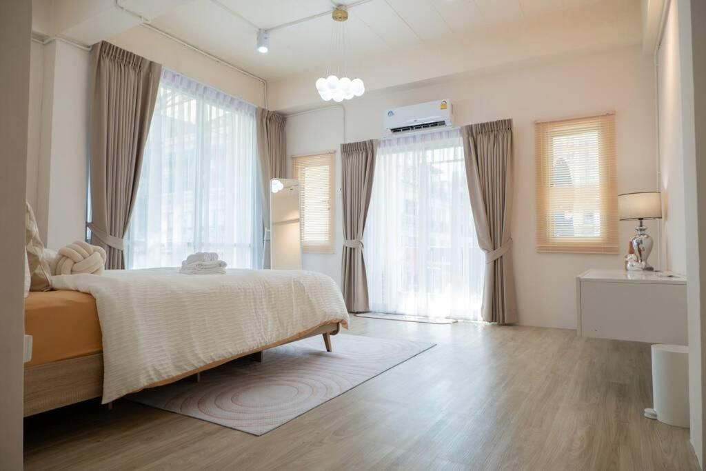 A hotel room with a bed, a bedside table, a lamp, and an air conditioning unit.