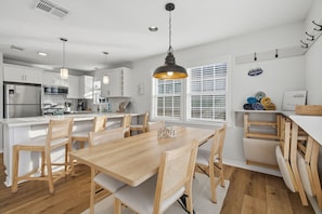 A modern kitchen with white cabinets, a stainless steel refrigerator, and a wooden dining table with chairs. - Garnele's retreat- come relax (Galveston)