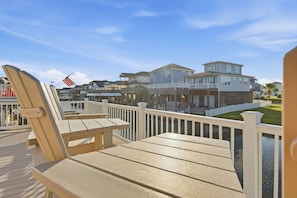 A wooden deck with chairs and a view of beachfront houses. - Garnele's retreat- come relax (Galveston)