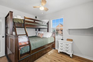 A bunk bed with a wooden ladder, a bedside table with drawers, a ceiling fan, and a window with blinds. - Garnele's retreat- come relax (Galveston)
