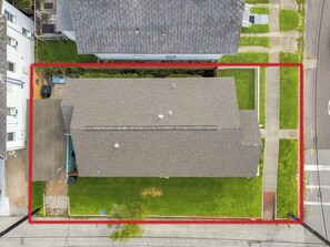 A rooftop with a flat surface, surrounded by a red boundary, and adjacent to a road with a sidewalk. - Old Flamingo Beach House (Galveston)