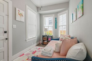 A bedroom with a bed, pillows, a rug, a nightstand, and wall art. - Old Flamingo Beach House (Galveston)