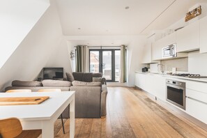 A modern loft apartment with a kitchen, dining area, and living space. - Bethnal Green Penthouse & Terrace (London)
