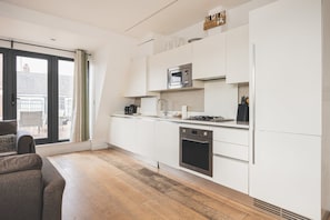 A modern kitchen with white cabinetry, a built-in oven, a microwave, and a gas stove. - Bethnal Green Penthouse & Terrace (London)
