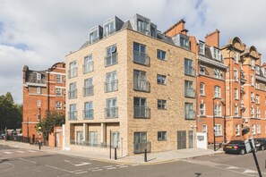 A multi-story residential building with a brick facade, multiple balconies, and a flat roof. - Bethnal Green Penthouse & Terrace (London)