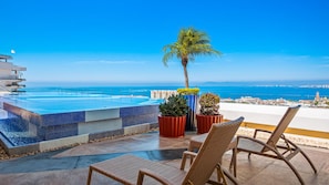 A rooftop infinity pool with a clear view of the ocean and cityscape.