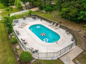 A rectangular outdoor pool with a surrounding deck, lounge chairs, and a fenced area. - Creek Mornings, Fire-Pit Nights • Cozy Cottage Near Thunder Ridge (Blue Eye)