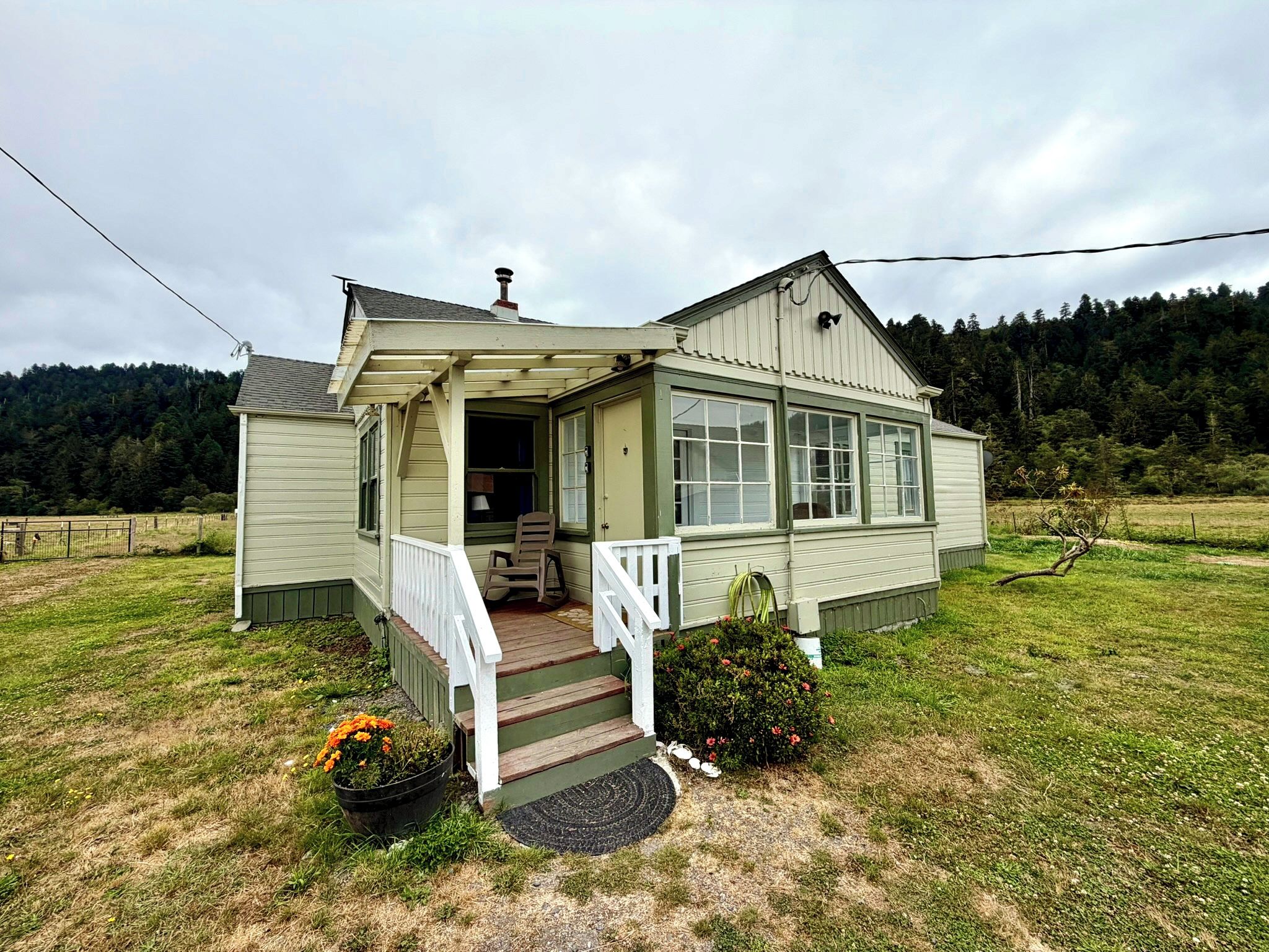 A single-story house with a porch, a front door, and a small garden area with flowers.