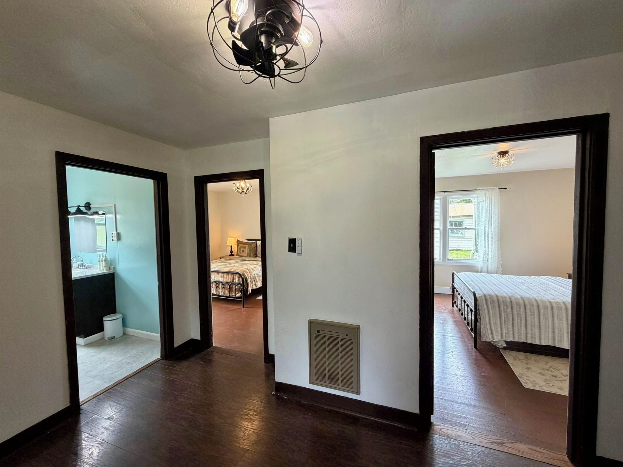 A hallway leading to a bedroom with a bed, a bathroom with a sink, and a kitchen area.