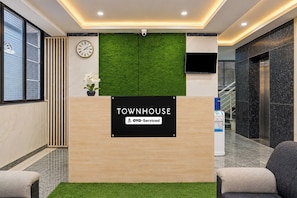 Una recepción con un cartel que dice 'TOWNHOUSE' y 'OYO-Serviced'.