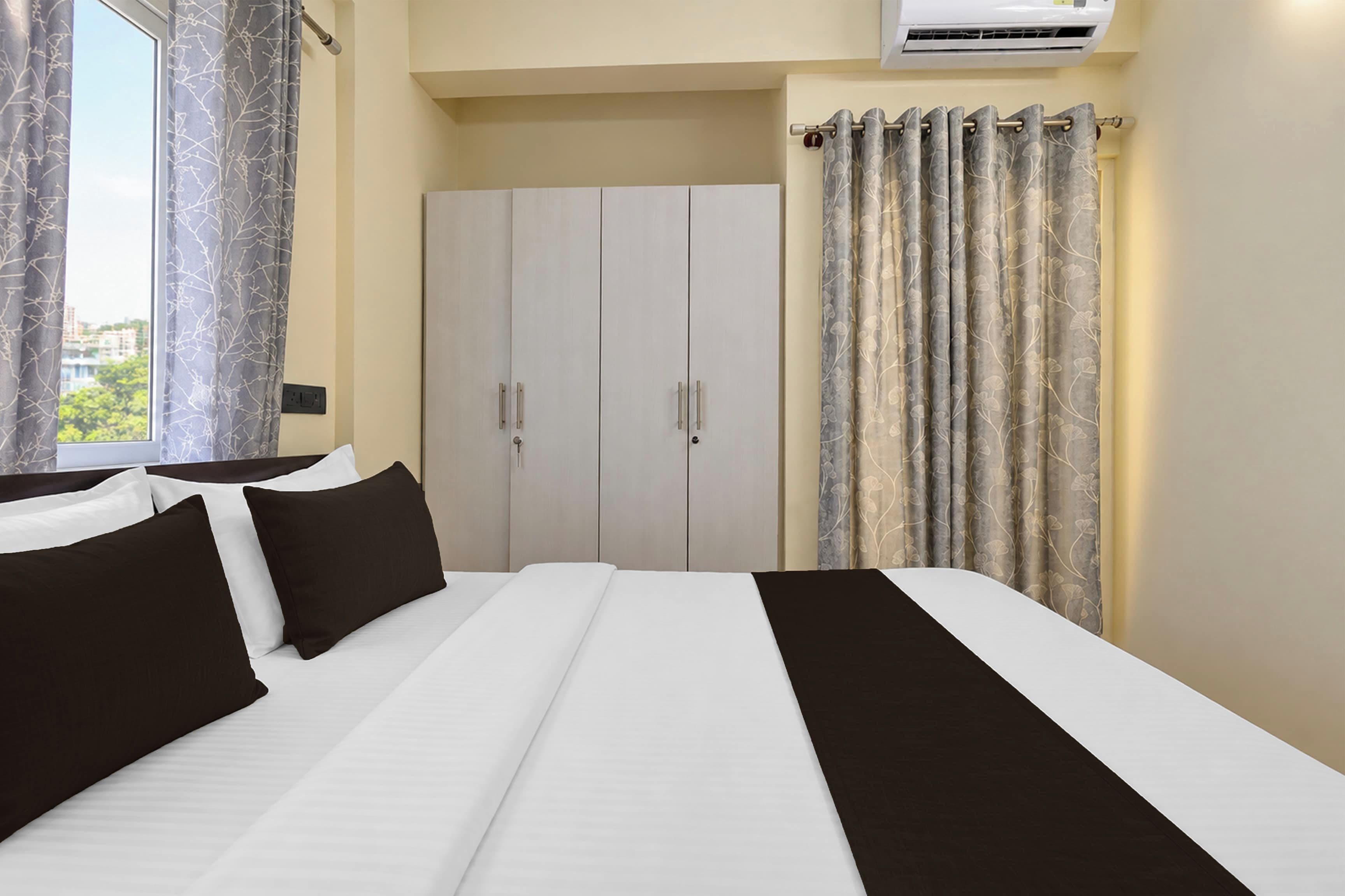 Una habitación de hotel con cama, armario y cortinas.