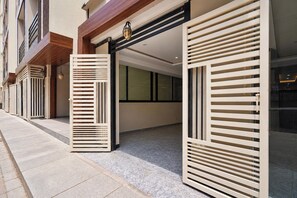 Entrada de hotel con diseño moderno, destacando un gran ventanal y un techo de madera.