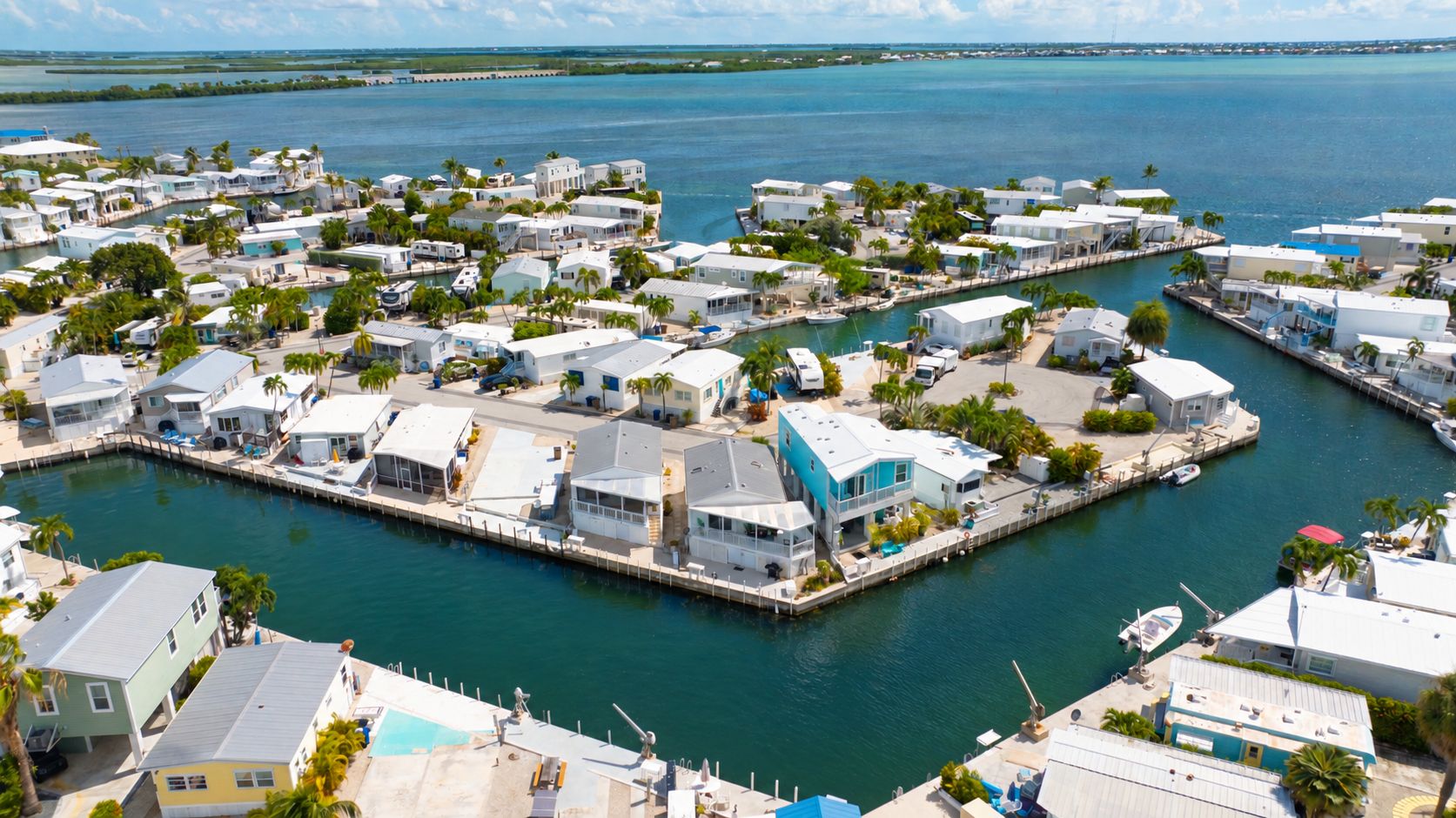 A marina with multiple docked boats, a variety of residential buildings, and a clear view of the surrounding water.