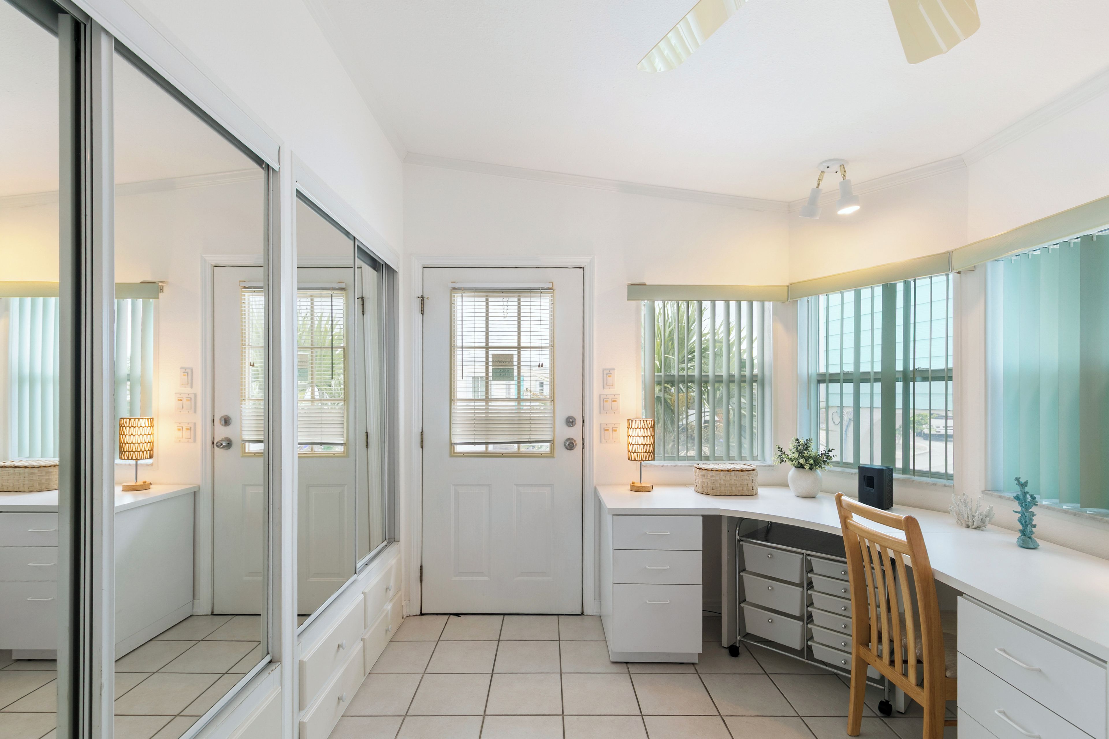 Een moderne keuken met witte kasten, een houten stoel en een groot raam.
