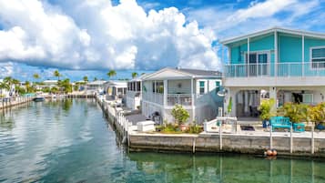 A waterfront property with a dock, a covered outdoor seating area, and a two-story building with a balcony.