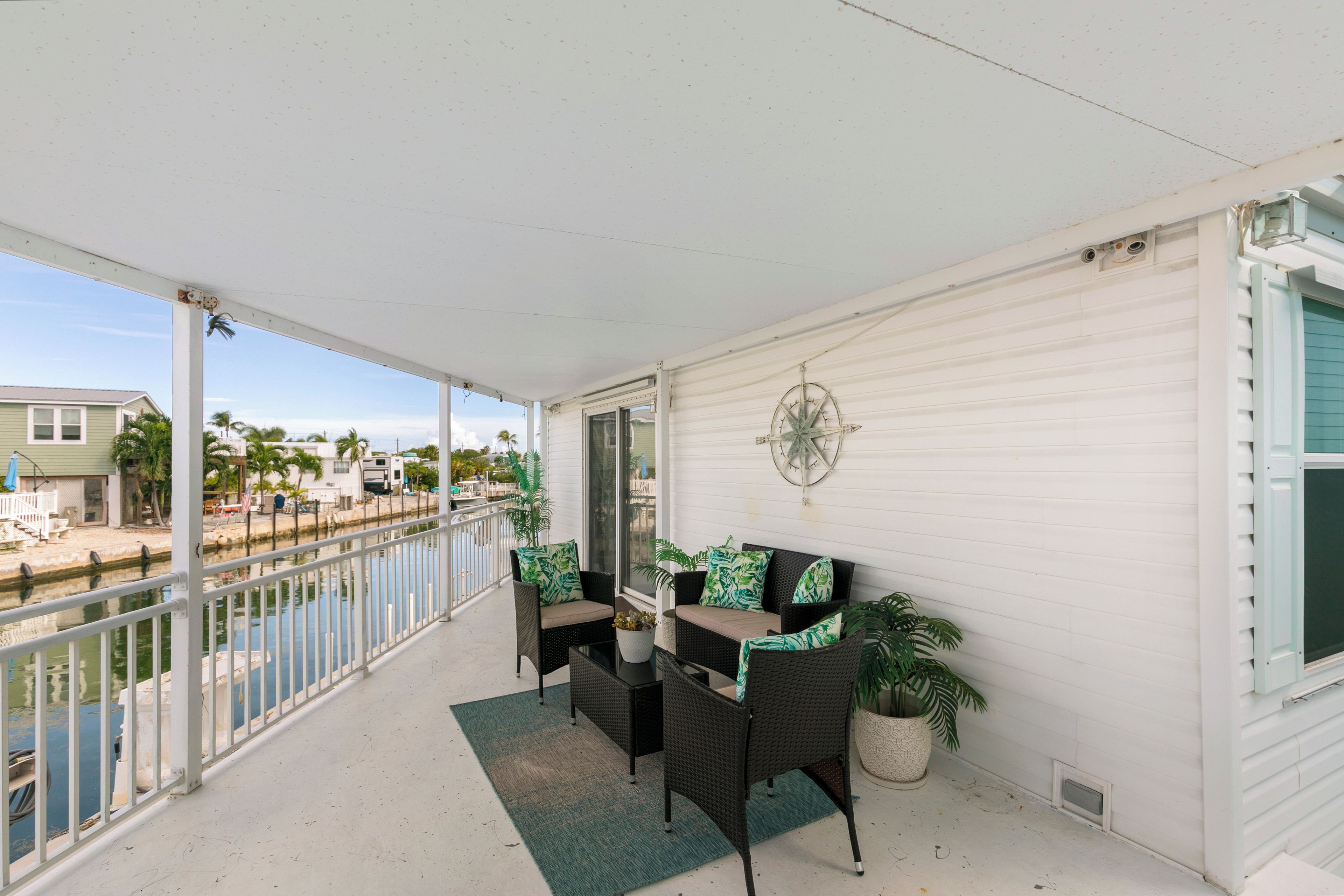 A balcony with a view of a marina, a dining table with chairs, and a decorative wall piece.