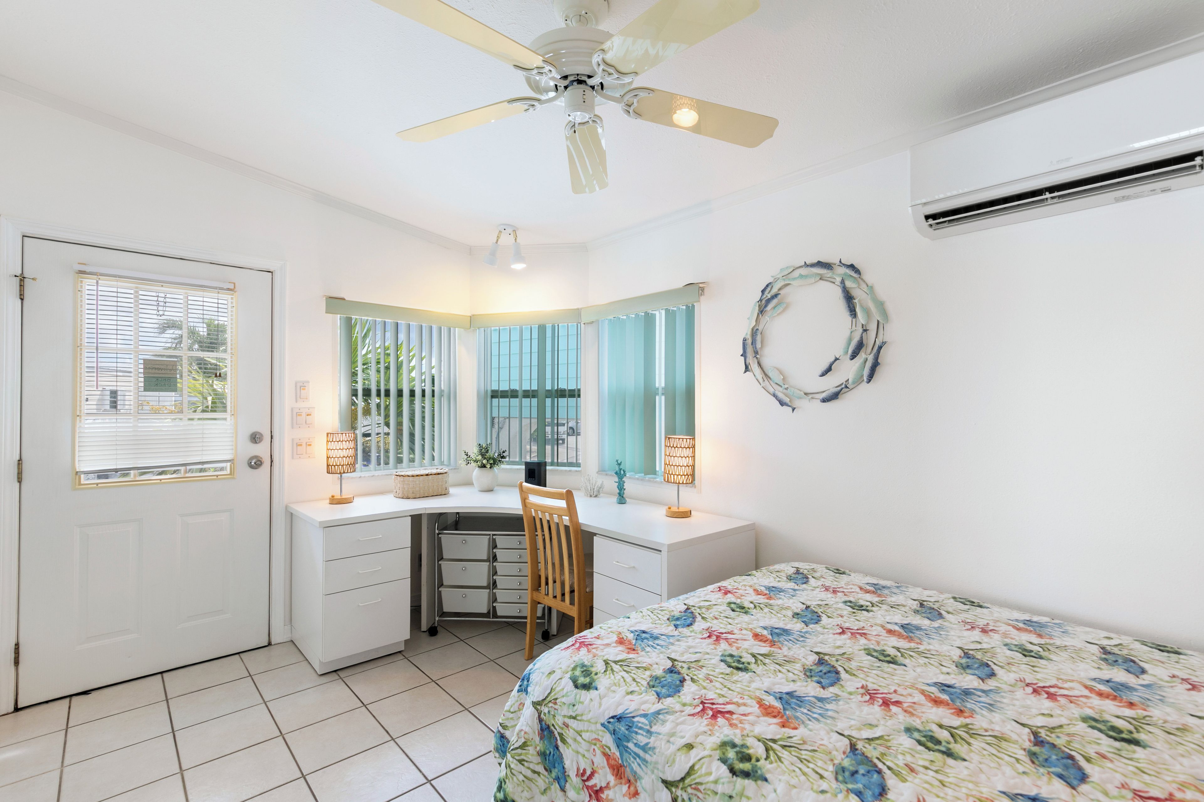 A bedroom with a bed, desk, chair, and a ceiling fan.