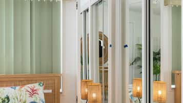 A hotel room with a bed, bedside lamps, a mirror, and a window with blinds.