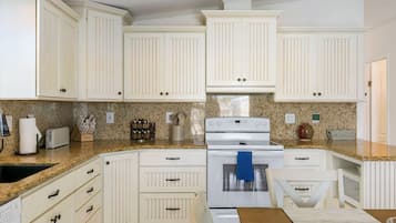 A kitchen with white cabinetry, a granite countertop, a stove, and a sink.