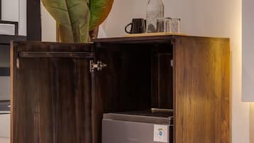 Ein Holzkabinent mit einem kleinen Gerät im Inneren, einer Pflanze obenauf und einer Wandleuchte.