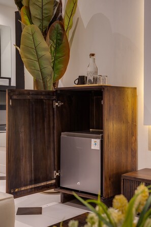 A wooden cabinet with a small appliance inside, a plant on top, and a wall-mounted light. - 2 BR Apartement Near Thomas Beach, Uluwatu (South Kuta)