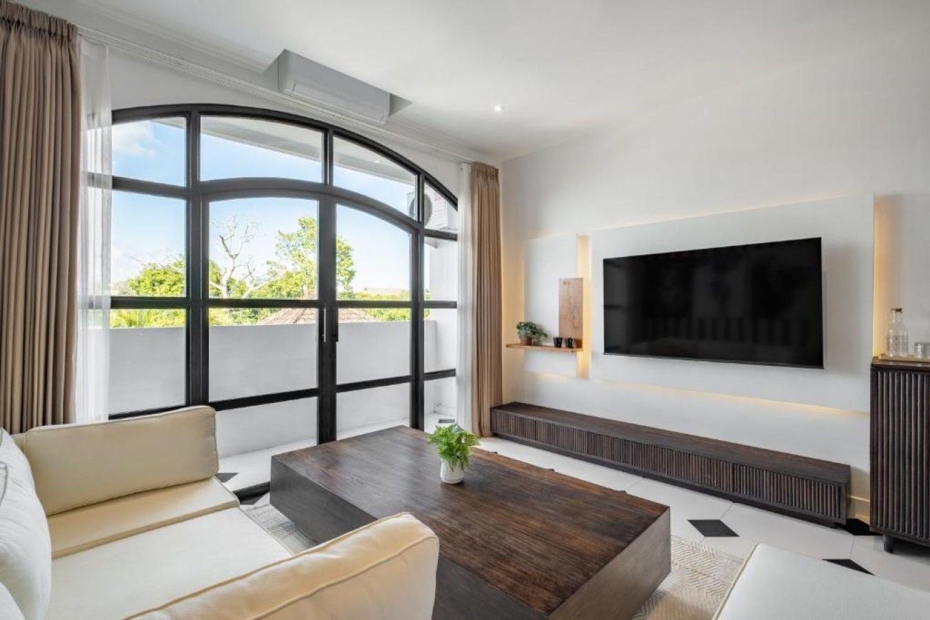 Ein modernes Wohnzimmer mit großem Fenster, Flachbildfernseher und einer Couch.