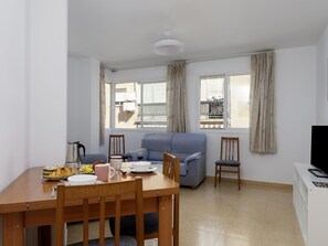 Een eetgedeelte met een tafel gedekt voor twee personen, een bank en een tv-meubel.