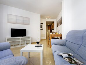 Een moderne woonkamer met een flatscreen televisie, een salontafel en een bank.