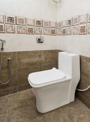 A bathroom with a toilet, shower, and decorative tiles.