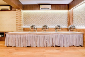 Taula de conferències amb estovell blanc, envoltada de cadires amb parts reflectants, en una sala amb panells de fusta i un mur amb disseny de maó.
