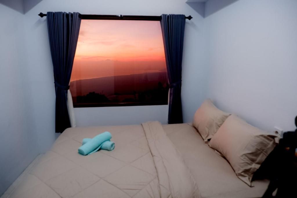 A bedroom with a bed, a window with curtains, and a view of the sky.