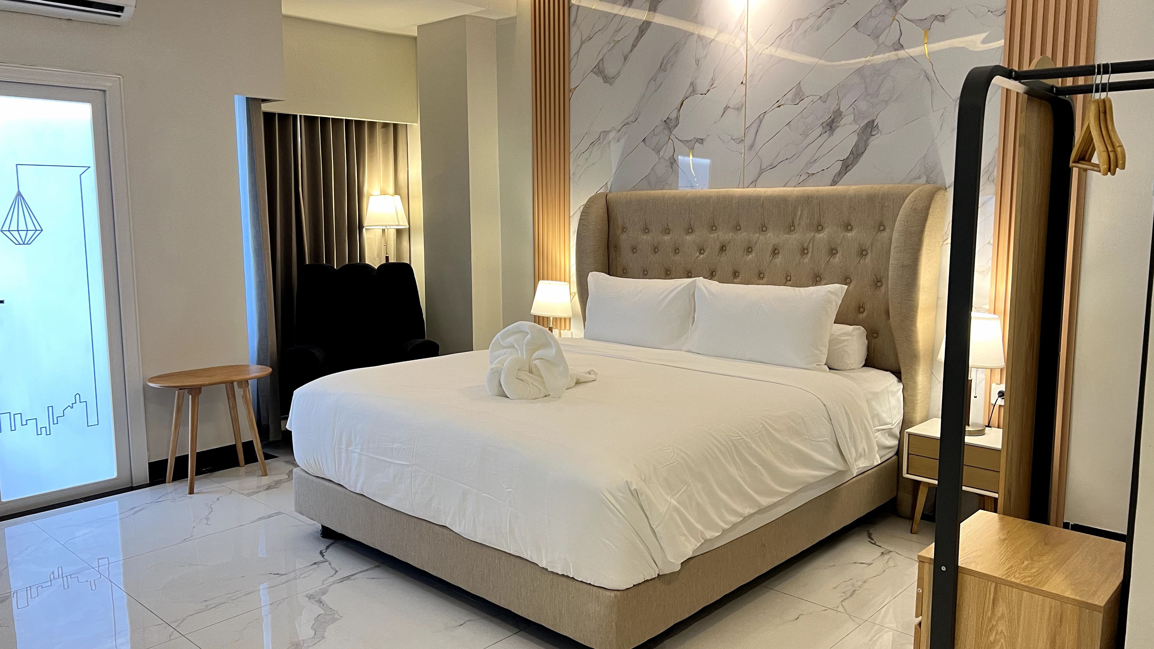 Een hotelkamer met een groot bed, een nachtkastje, een lamp en een spiegel.