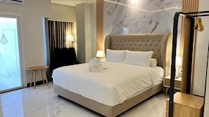 A hotel room with a large bed, a bedside table, a lamp, and a mirror. - Qafotel Boutique (Balikpapan)