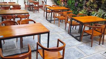 Un restaurant avec des tables et des chaises en bois, entouré de différentes sortes de plantes.